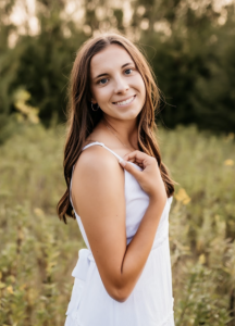 A woman wearing a white dress, smiling. 